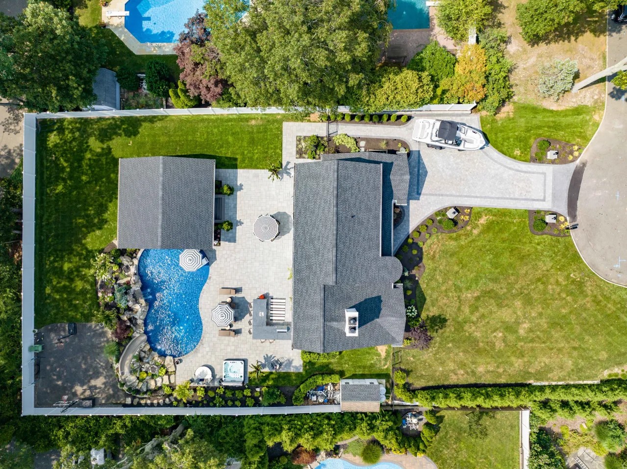 Aerial view of a completed backyard with pool, patio, pavilion and paver driveway